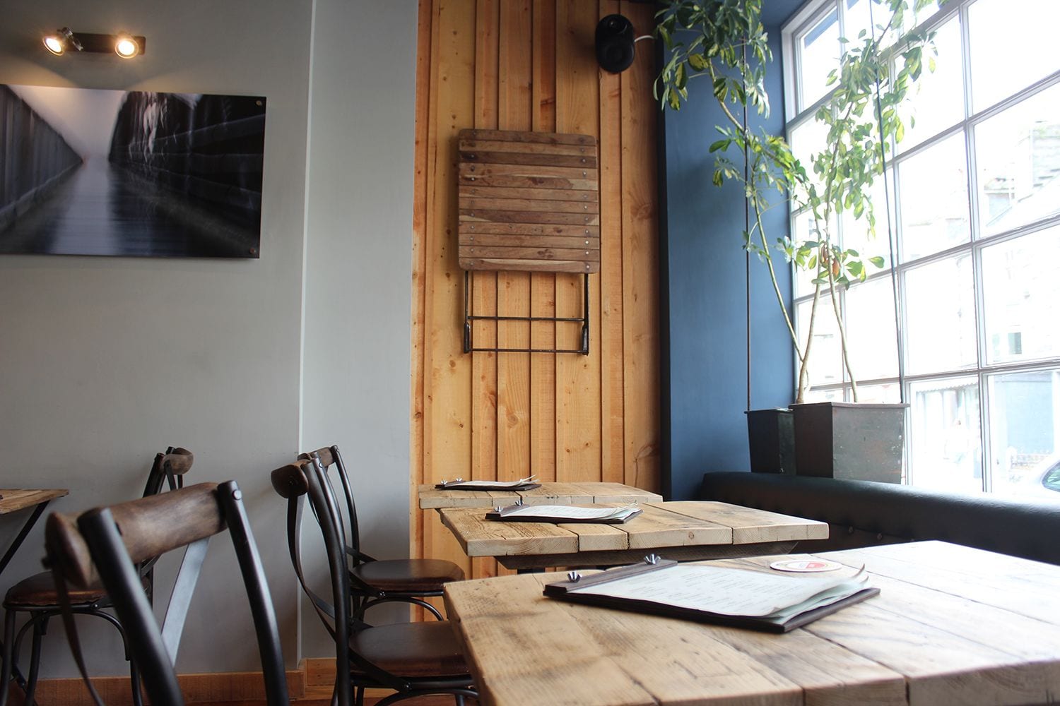 A restaurant interior with wooden walls, a large window, and a table with menus.
