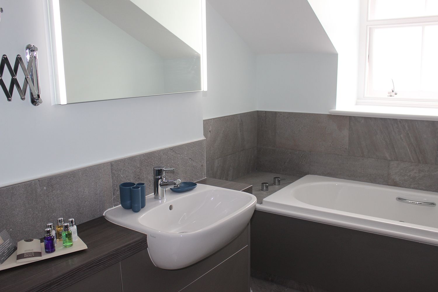 Ein modernes Badezimmer mit einem weißen Waschbecken, einer Badewanne und einem großen Spiegel.