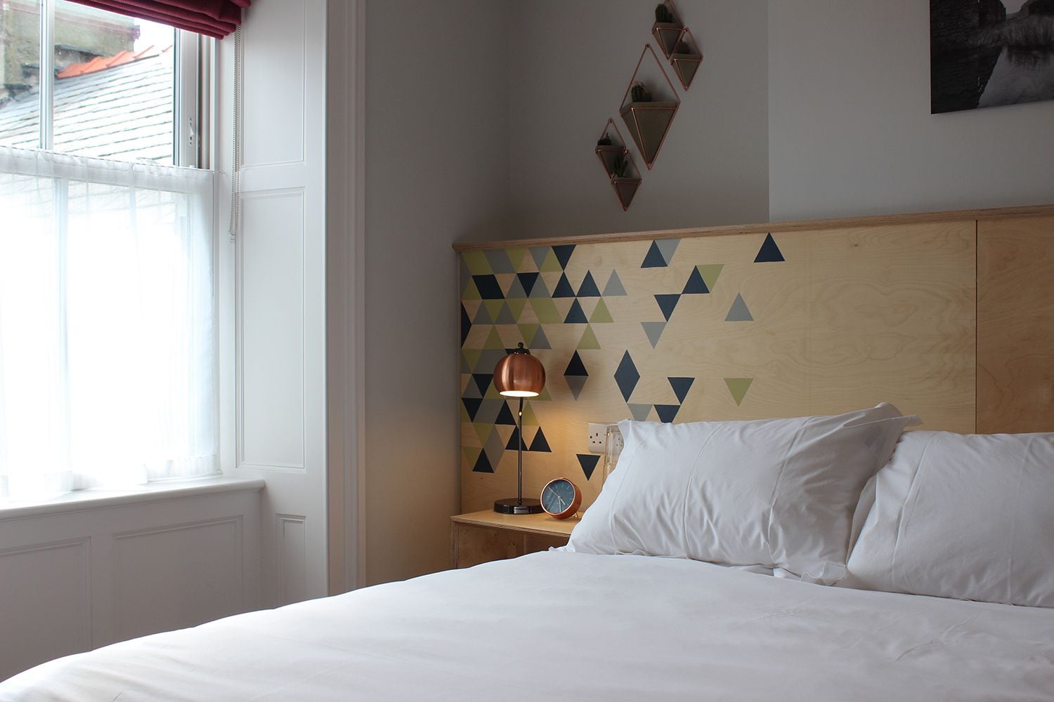 A bedroom with a bed, a nightstand, a lamp, and a wall clock.