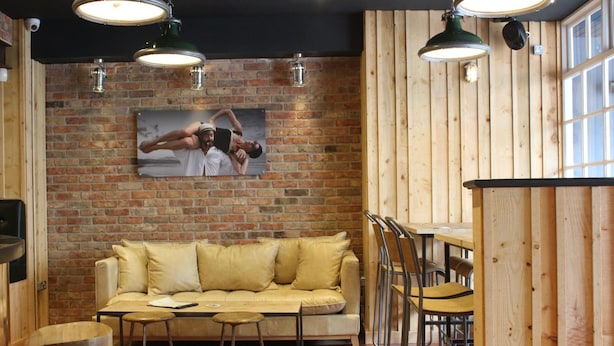 A cozy room with a brick wall, a sofa, a table, and chairs. - The Tilman (Barmouth)