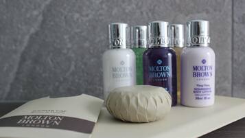 Cuatro botellas de loción corporal Molton Brown y un gorro de ducha sobre una mesa.