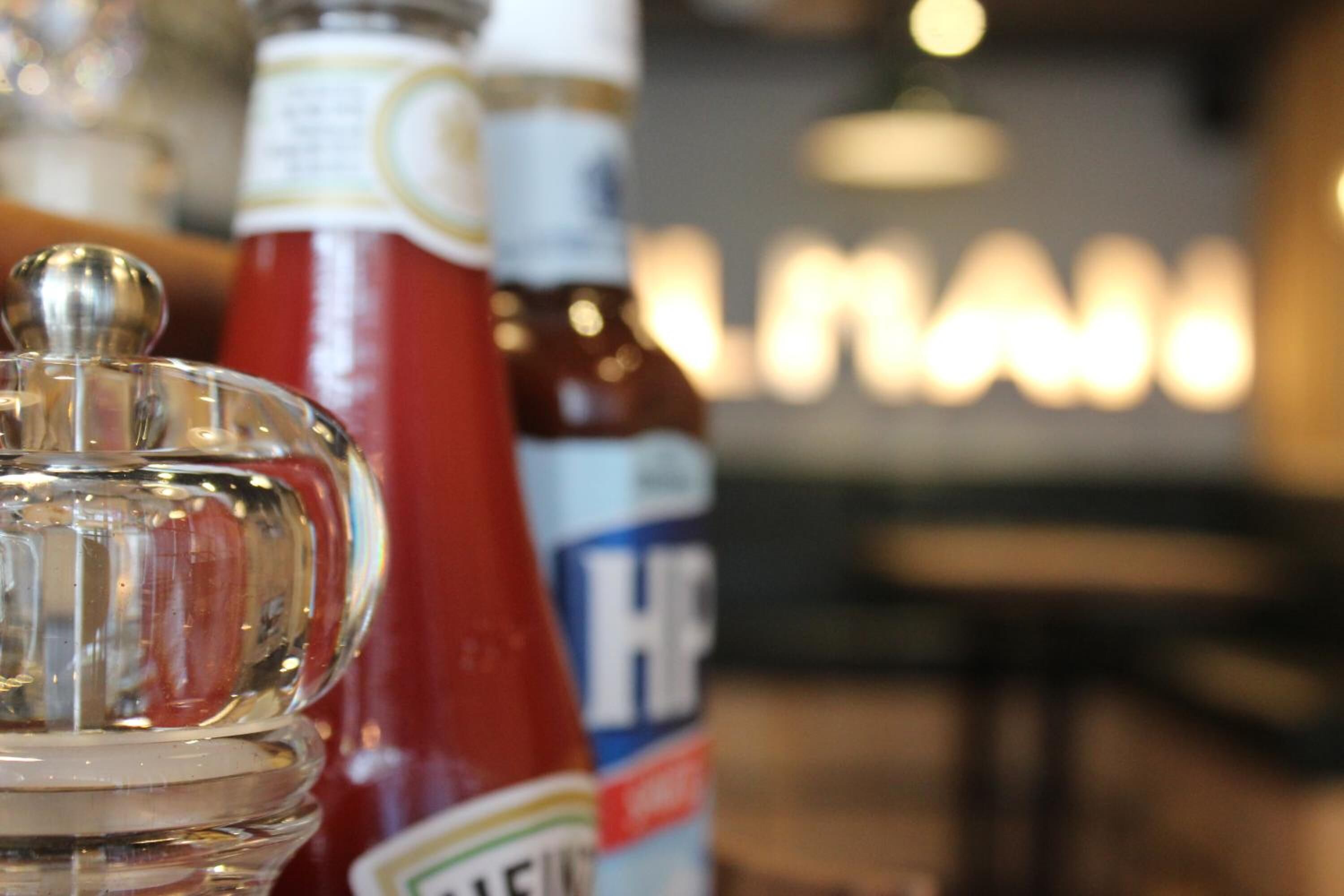 A clear view of a condiment bottle, a ketchup bottle, and a bottle with a blue label.