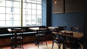 A restaurant interior with wooden tables and chairs, large windows, and decorative wall panels. - The Tilman (Barmouth)