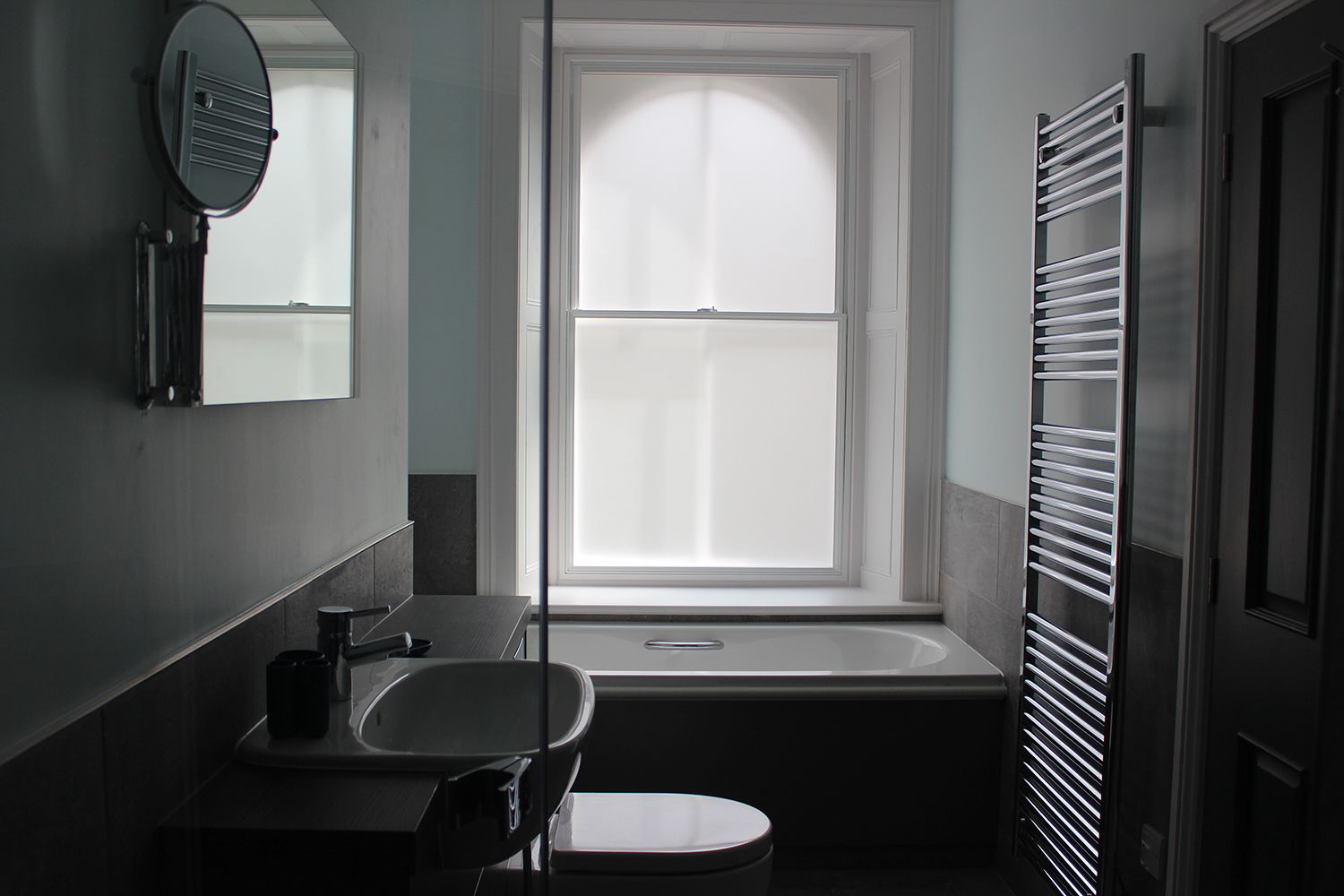 Un bagno con lavandino, specchio e finestra.