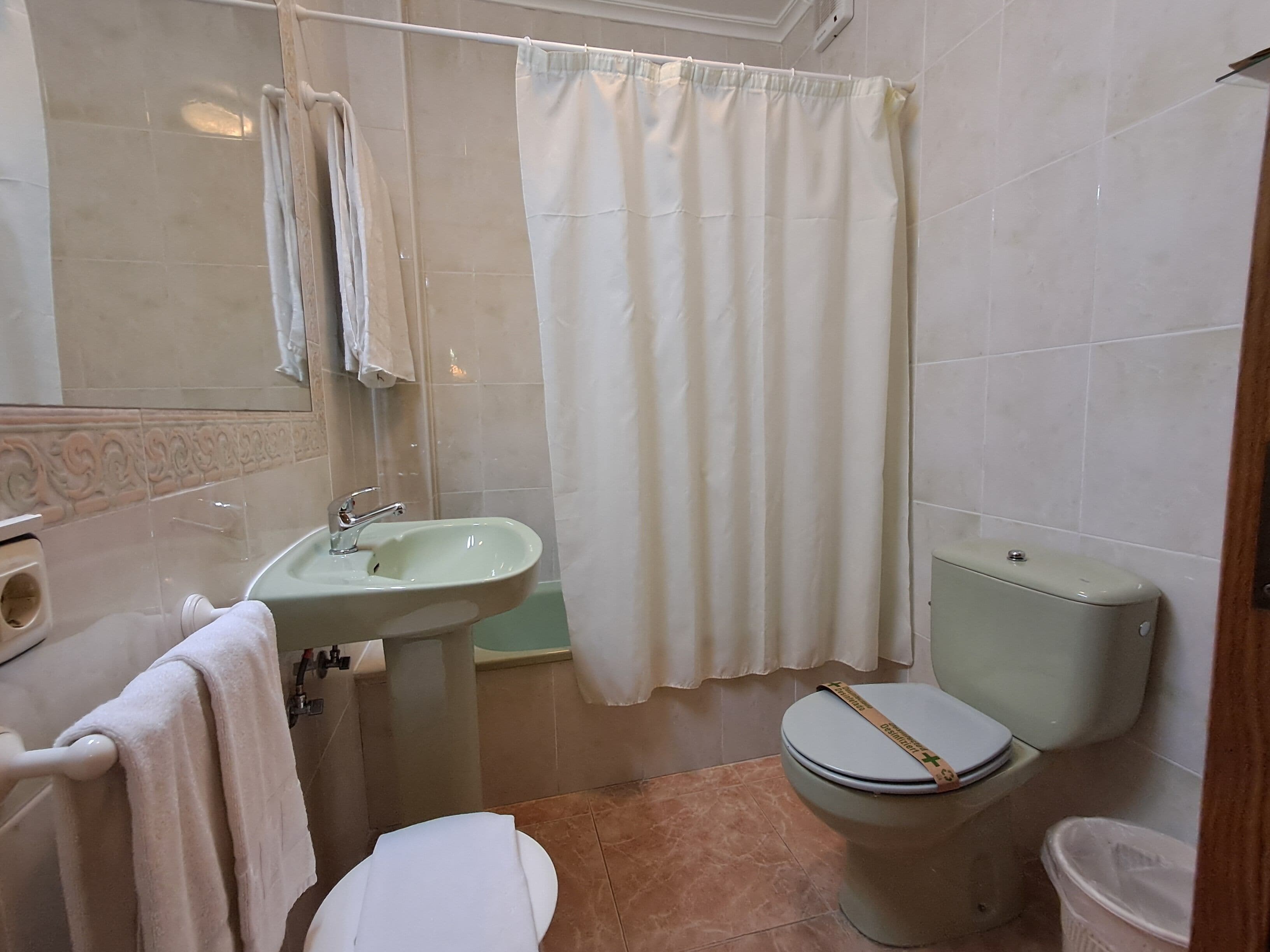 Un baño con lavamanos, inodoro y cortina de ducha.