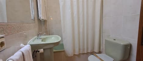 Un baño con lavamanos, inodoro y cortina de ducha.