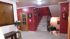 A hallway with a wooden bench, a door, a staircase, and a fire extinguisher.