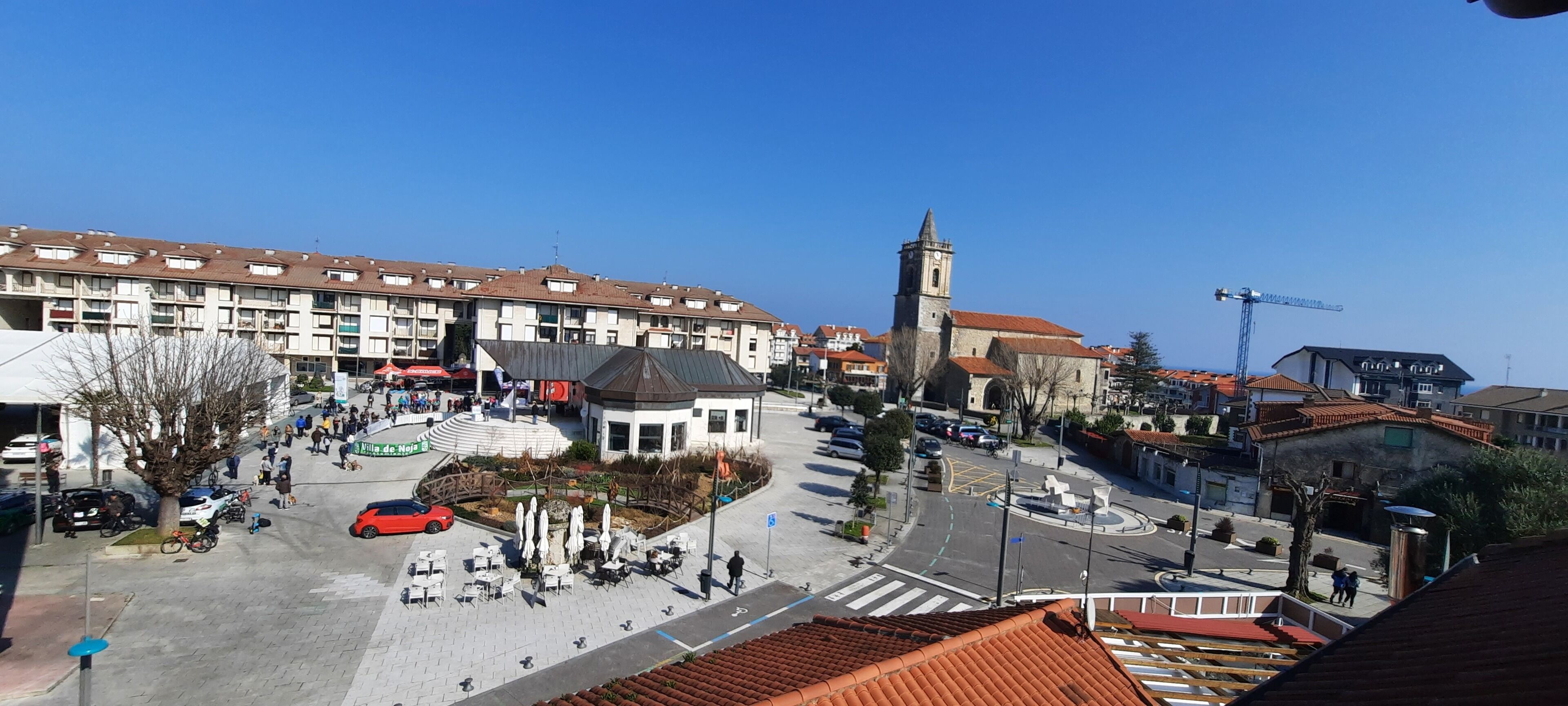 A public square with a central fountain, surrounding buildings, and a church tower.