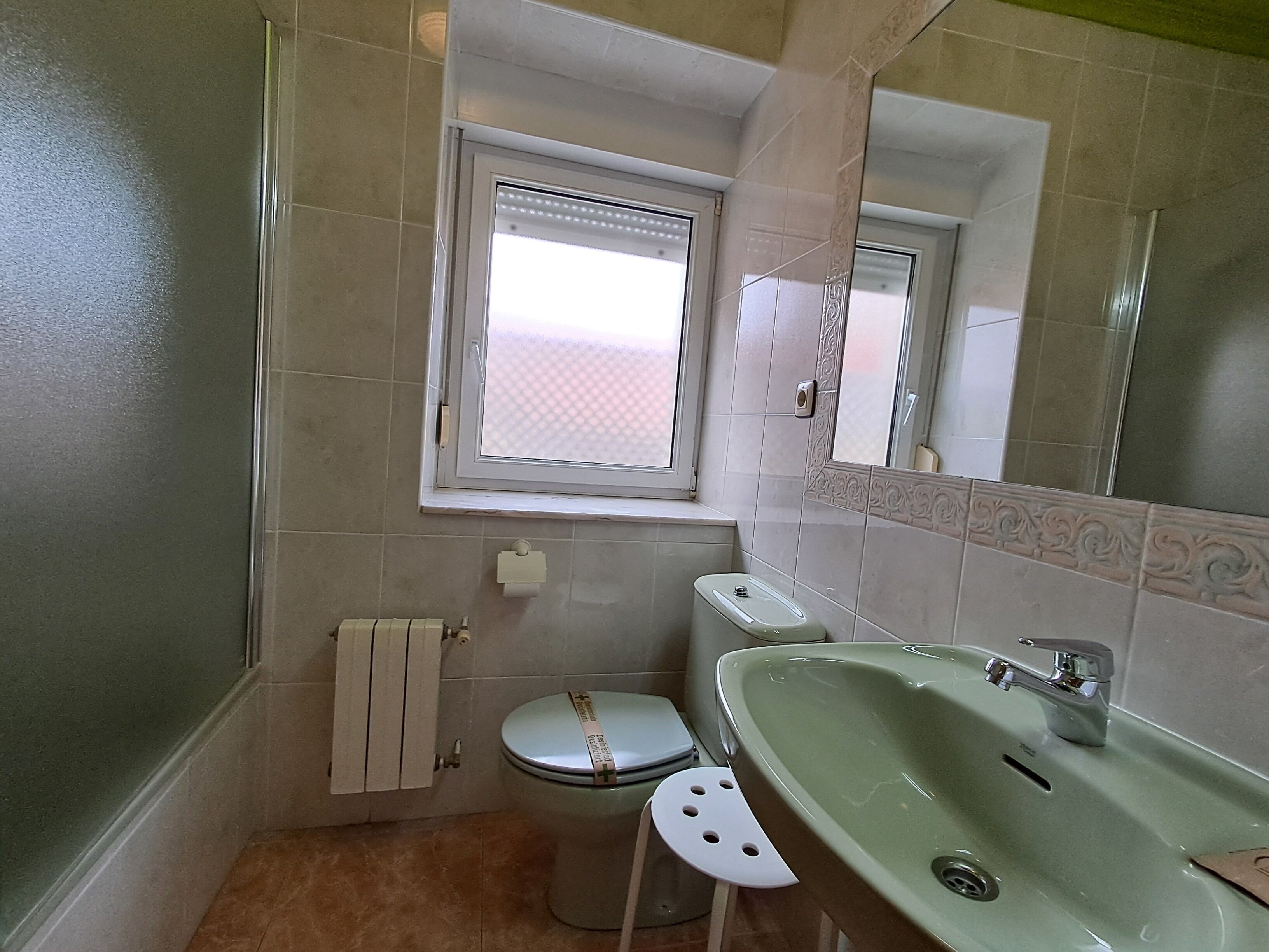 A bathroom with a toilet, sink, and window.