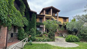 A courtyard with a brick building, a wooden fence, and a garden with various plants and a small pond. - Casa Rural La Covacha (Losar de la Vera)