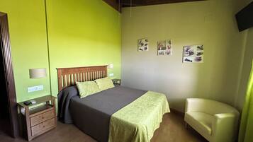 Een slaapkamer met een bed, nachtkastjes, een stoel en wanddecoraties.