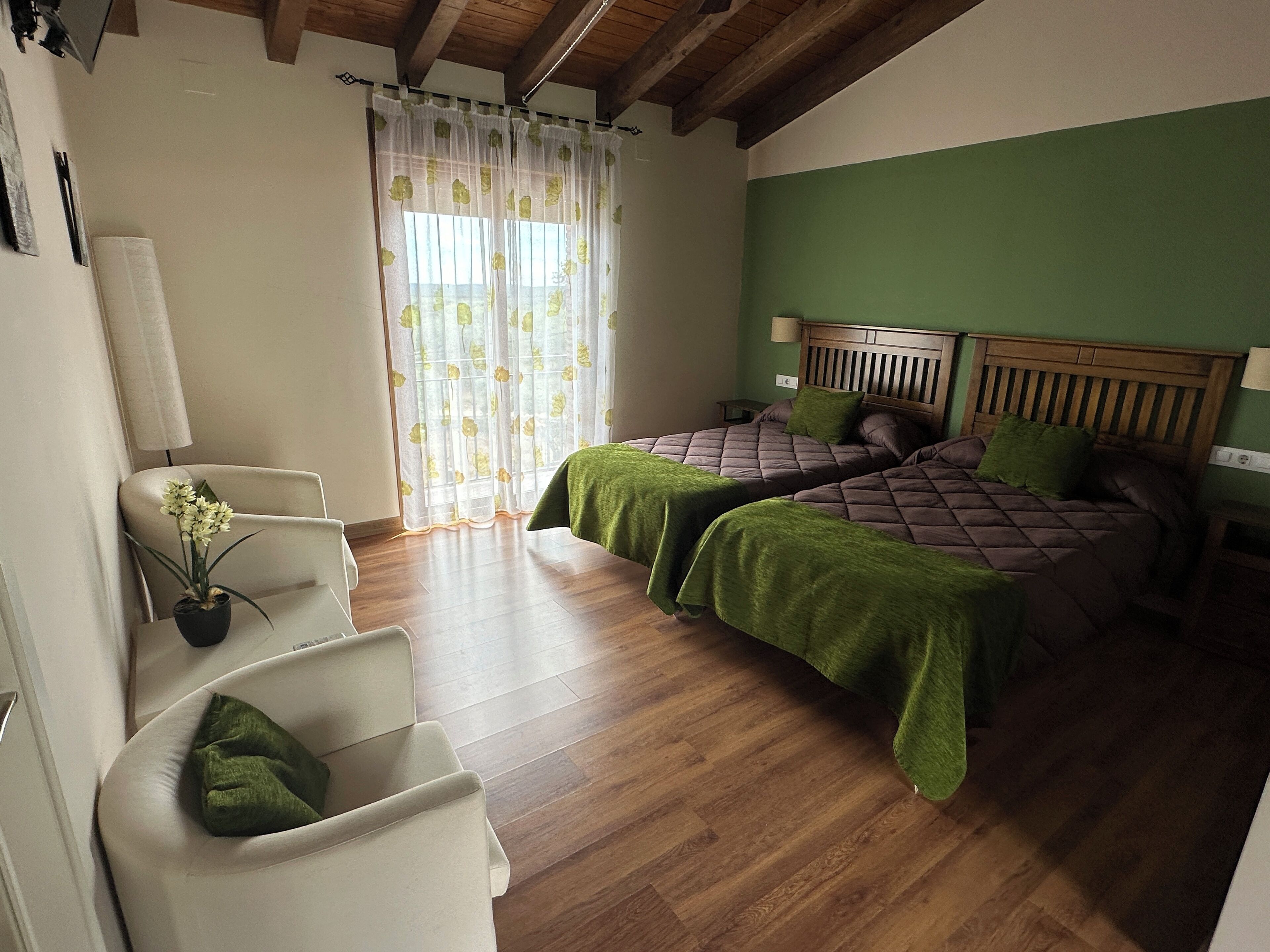 Een slaapkamer met twee bedden, een stoel, een lamp en een raam met gordijnen.