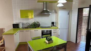 A compact kitchen with white cabinets, a green countertop, a microwave, a sink, a stove, and a refrigerator.