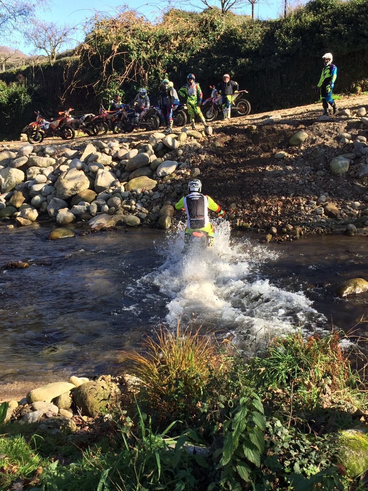 A motocross event with riders on bikes navigating a rocky stream.