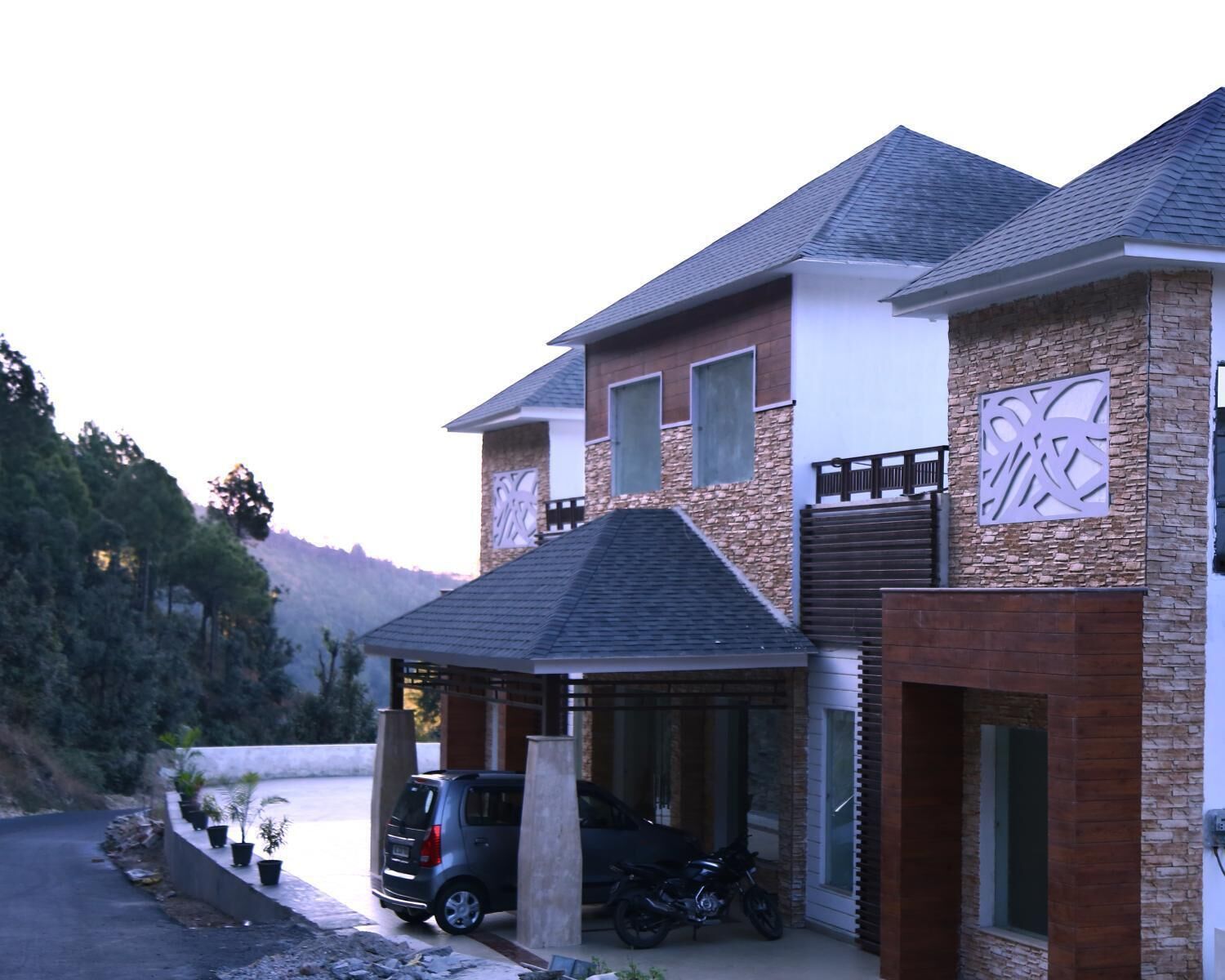 A two-story house with a garage, a covered driveway, and a mountain backdrop.