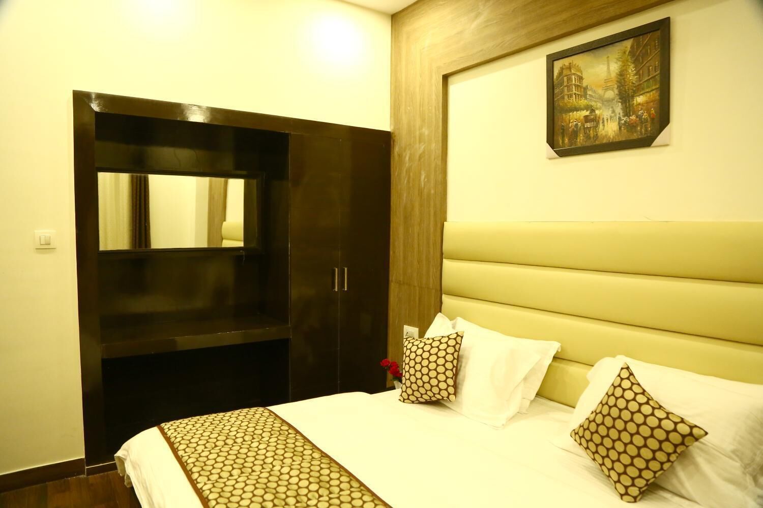Ein Hotelzimmer mit einem Bett, einem großen Spiegel, einem Holzschrank und einem Bild an der Wand.