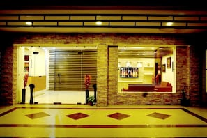 Un vestíbulo de hotel con una recepción, un área de estar con sofá y una pantalla de televisión.