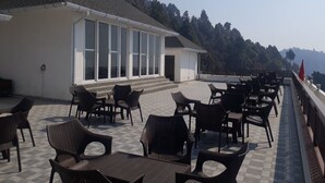 Una terraza con mesas al aire libre y un edificio con ventanales grandes.