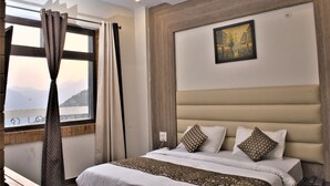 Una habitación de hotel con una cama grande, un cuadro en la pared y una ventana con cortinas.