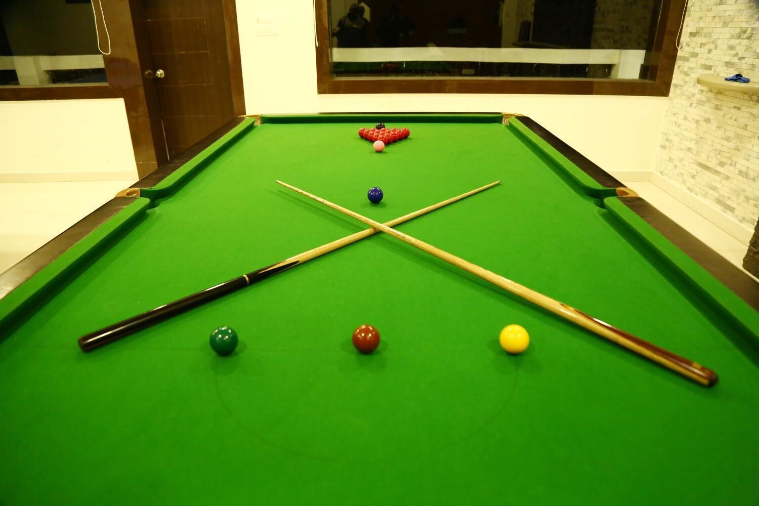 A pool table with balls and cues, a window with a view, and a door.