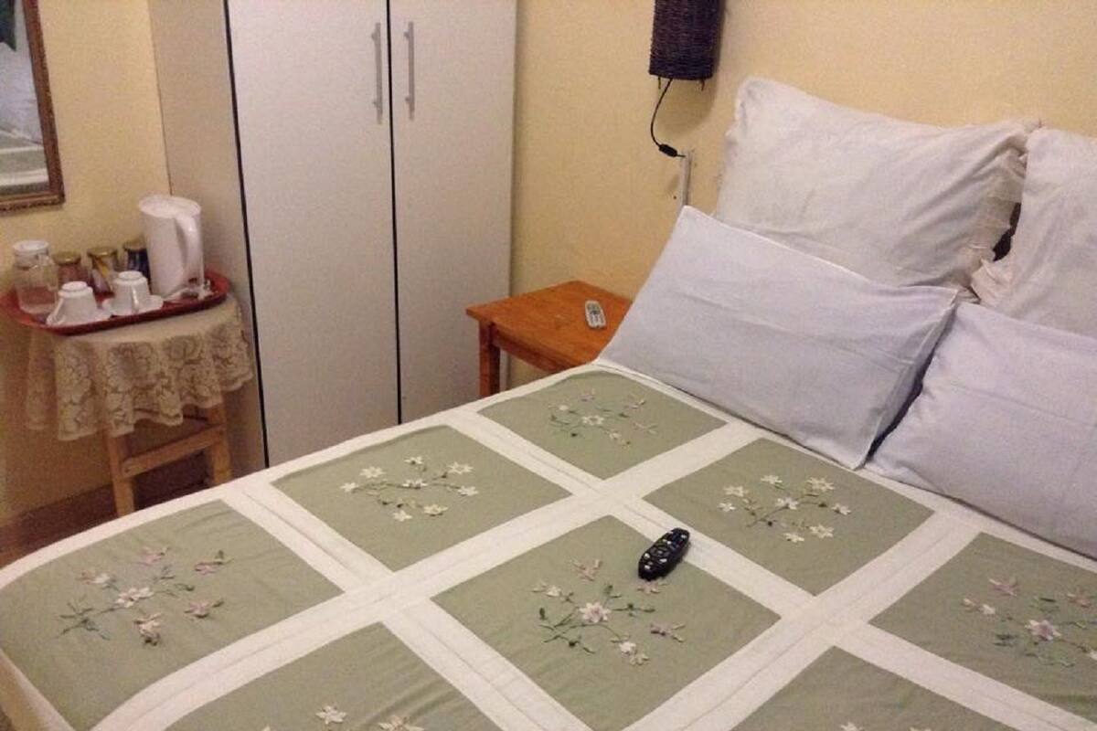 A bedroom with a bed, a nightstand, a wardrobe, and a small table with a lamp.