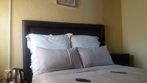 Un lit avec deux oreillers et une télécommande posée sur le lit.