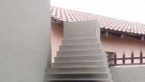 Un four extérieur en béton, doté d’un toit recouvert de tuiles, d’une plante en pot et d’un mur agrémenté d’une clôture décorative.