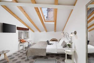 Un dormitorio con tragaluz, una cama, un escritorio y un televisor.