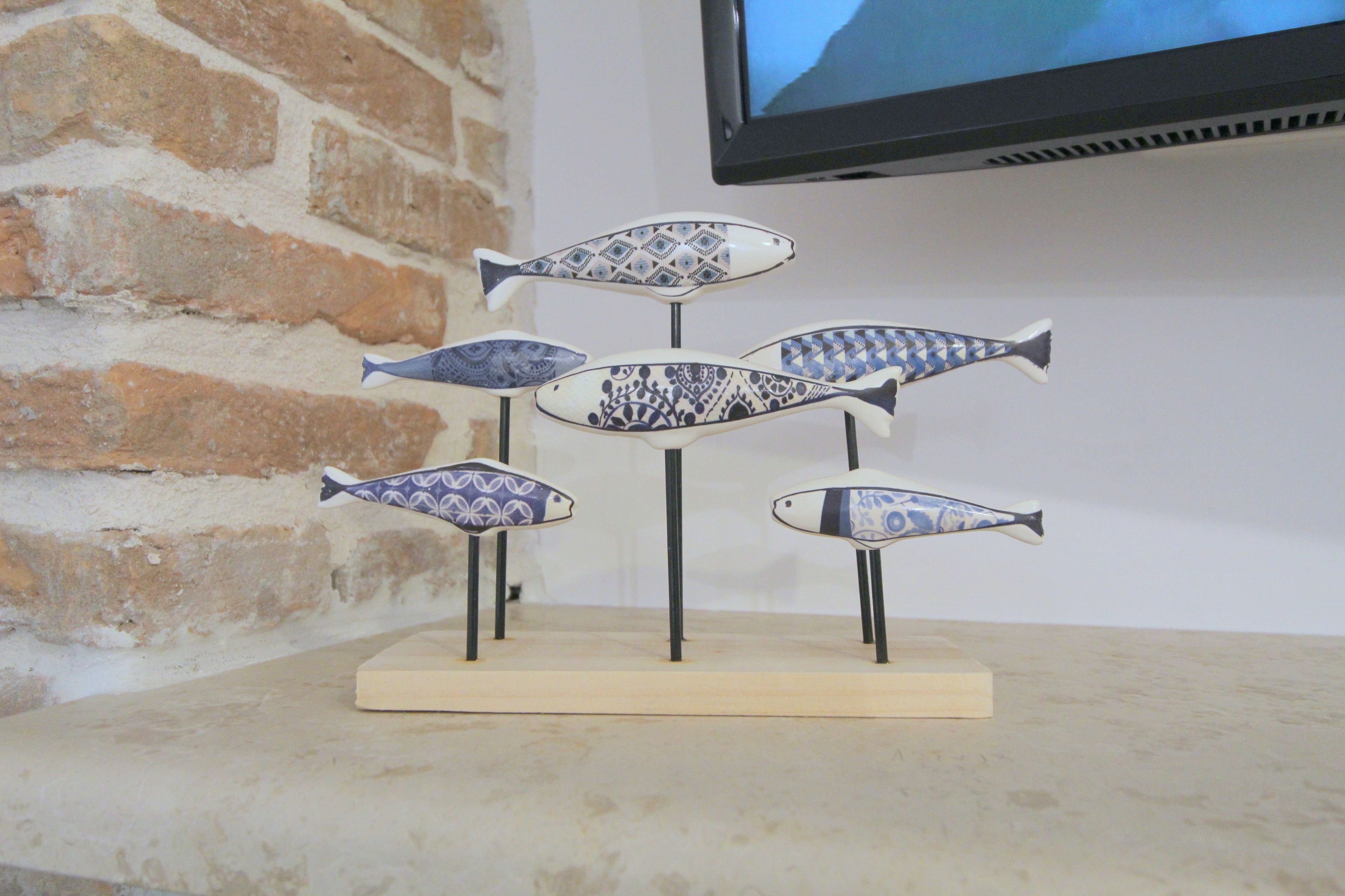 A display of fish-shaped ceramic pieces on a wooden base.