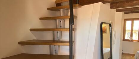 Una escalera de madera con barandilla negra que da a una plataforma.