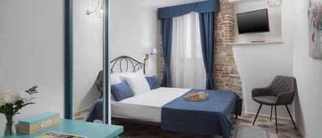 Un dormitorio con cama, escritorio, silla, televisión y ventana con cortinas.