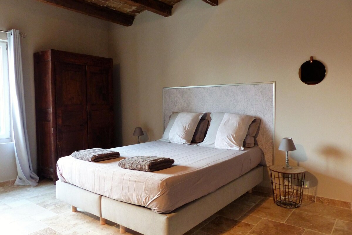 Un dormitorio con una cama, dos lámparas de noche, un armario de madera y un reloj de pared redondo.