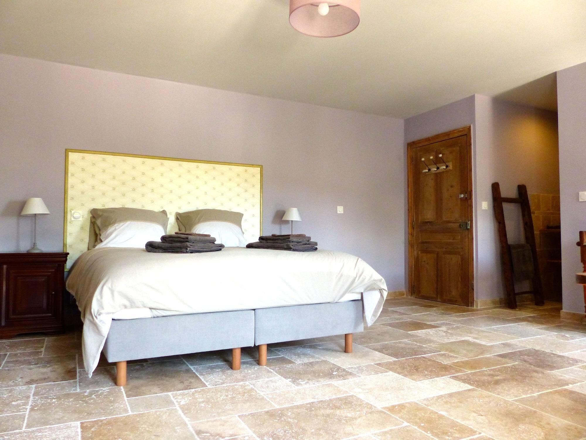 A bedroom with a bed, two bedside tables, a wooden door, and a tiled floor.