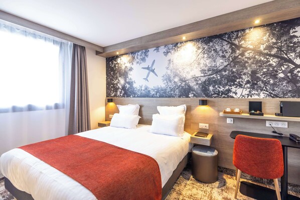 Habitación de hotel con una cama grande, un escritorio, una silla y un mural en la pared.