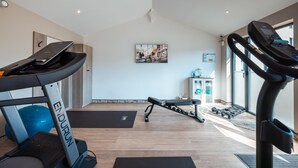 Une salle de sport à domicile équipée d’un tapis de course Endurance, d’un banc et de poids.