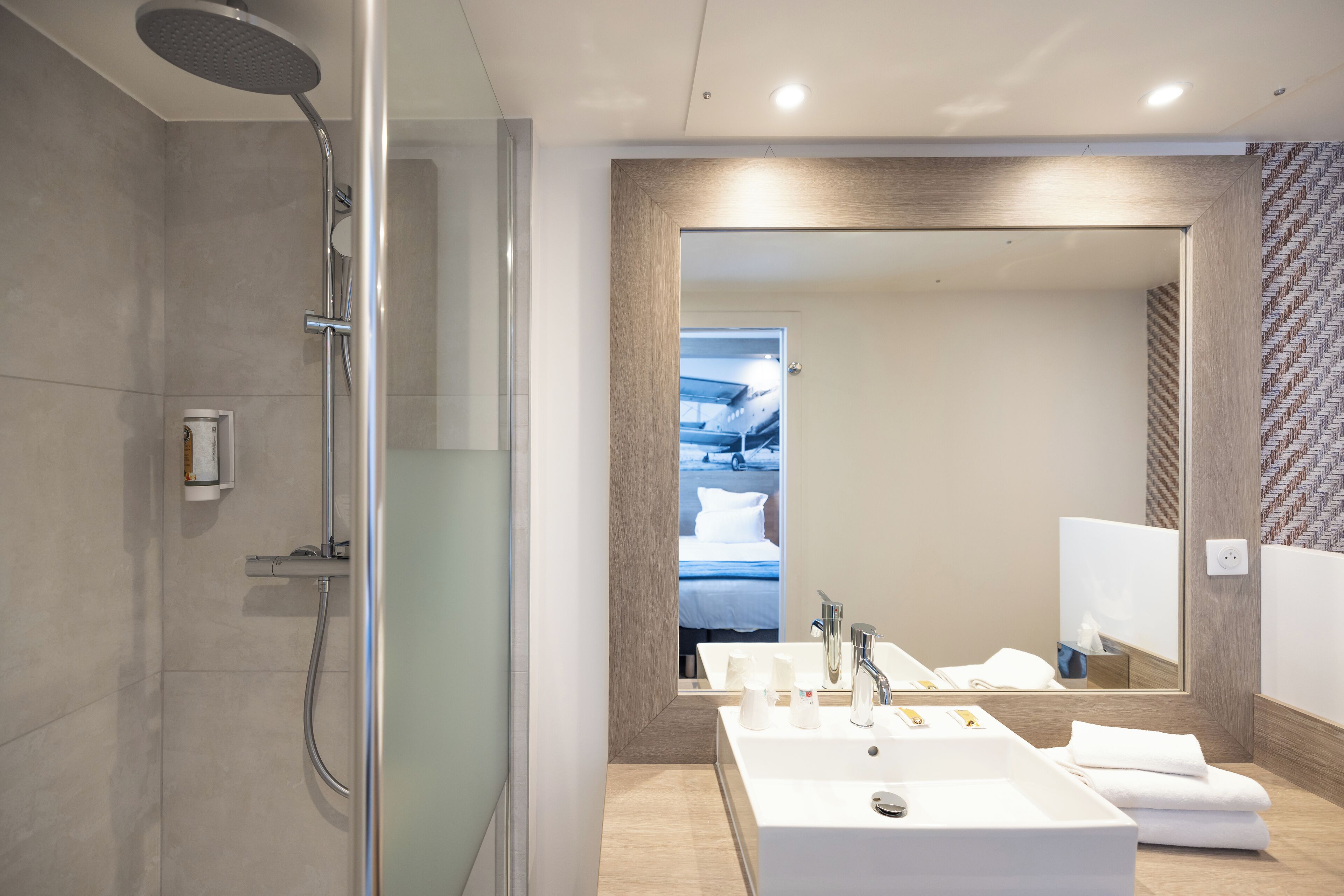 Une salle de bain moderne avec une douche, deux lavabos et un grand miroir.