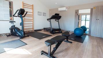 Une salle de sport à domicile équipée de matériel d’exercice, d’un tapis de course et d’un banc.