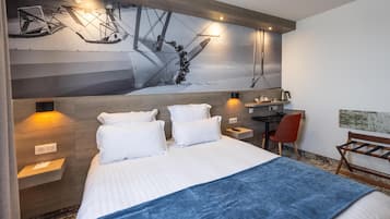 Una camera d'albergo con un letto grande, una scrivania, una sedia e un'opera d'arte appesa al muro.