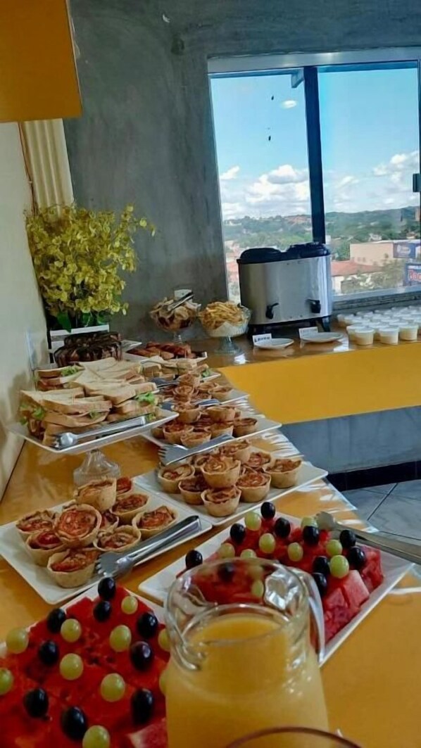 A breakfast buffet with various food items and a large window view. - Hotel Diniz (Barra do Corda)