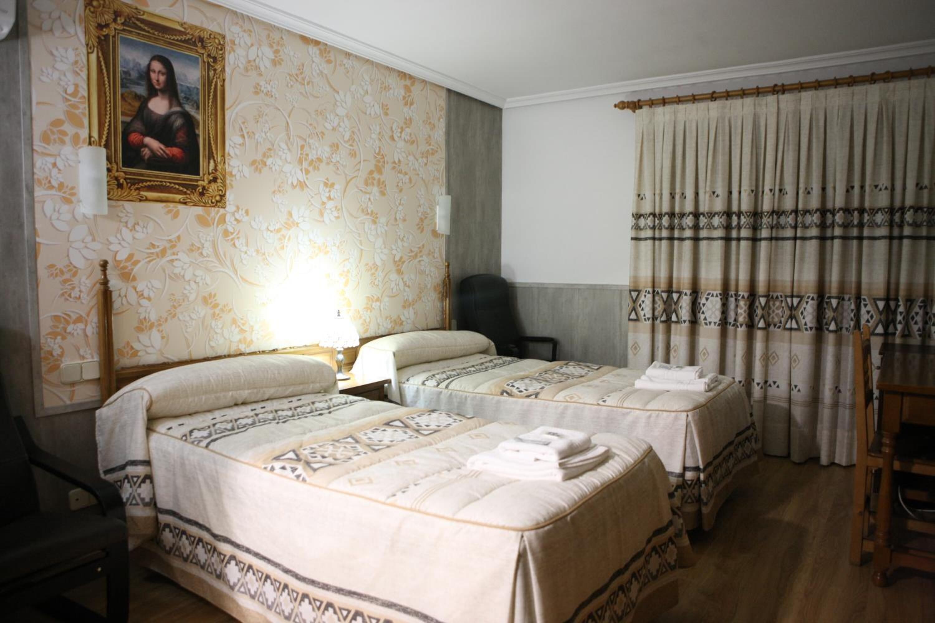 Een hotelkamer met twee bedden, een stoel, een bureau en een schilderij aan de muur.