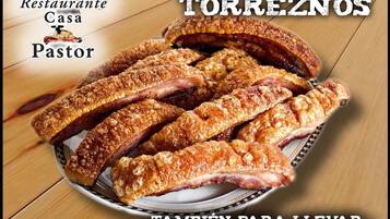 Un plato de panceta de cerdo asada, también conocida como 'torreños', sobre una mesa de madera.