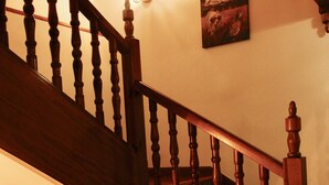 A wooden staircase with a handrail, a wall-mounted light fixture, and a framed artwork. - Hotel Plaza (Riaza)