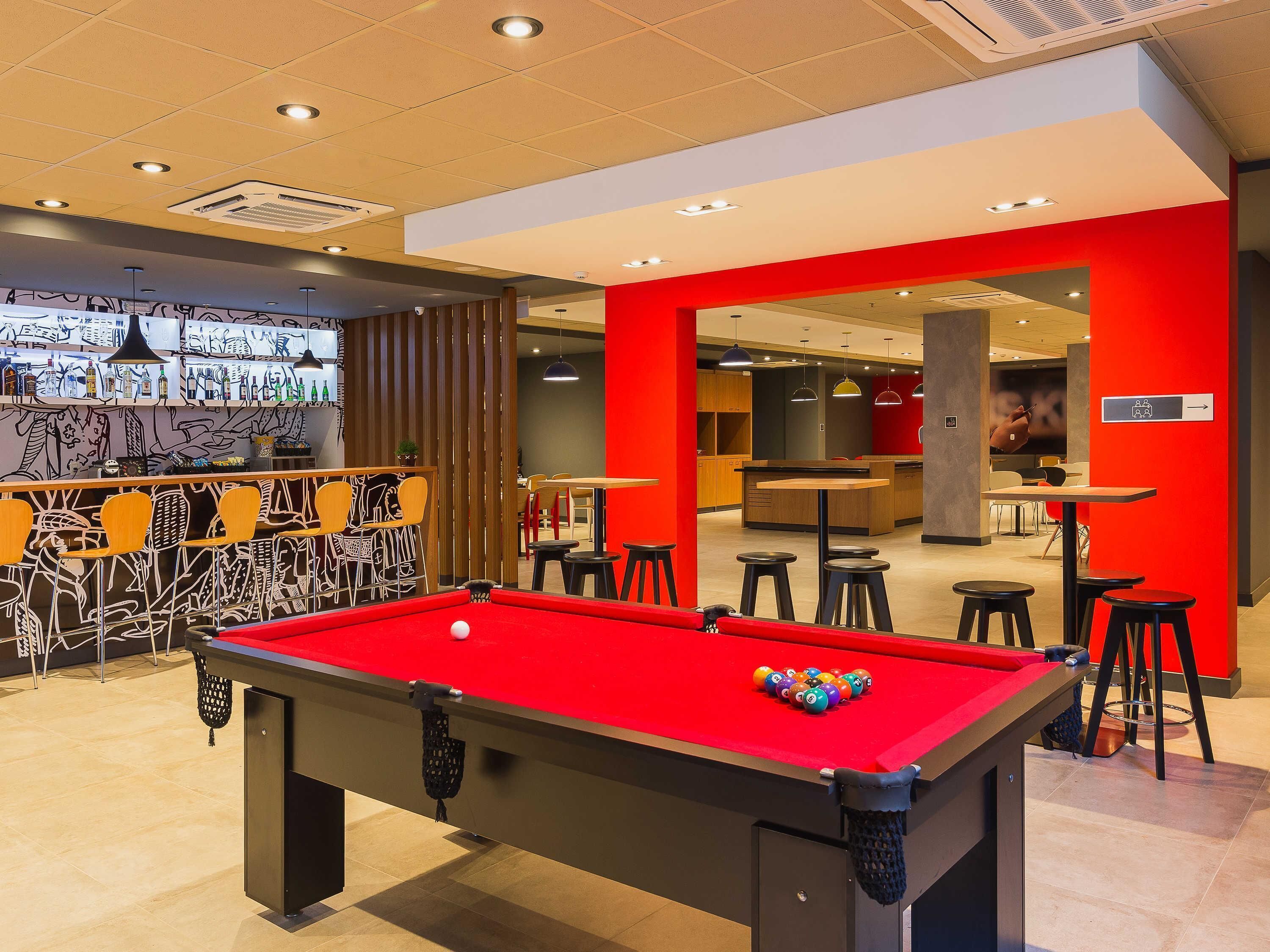 A pool table with balls, a bar area with chairs, and a dining area with stools.