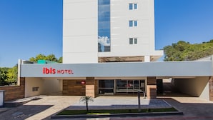 Un moderno edificio de hotel con techo plano, ventanas grandes y un letrero que dice 'ibis HOTEL'.