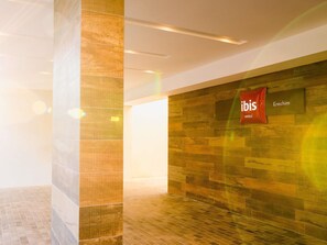 A hotel lobby with a stone wall, a sign for ibis hotels, and a tiled floor. - ibis Erechim (Erechim)