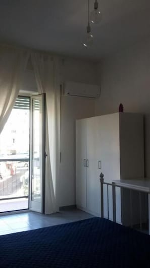 A bedroom with a bed, a wardrobe, a desk, and a large window with curtains. - B&B San Francesco (Mendicino)