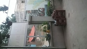 Ein zweistöckiges Gebäude mit flachem Dach, einem Balkon im oberen Stockwerk und einer Treppe, die zu diesem führt.