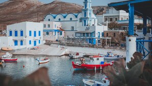 A harbor with boats, a church, and a mountain in the background. - Theoxenia Suites & Apartments (Kasos)