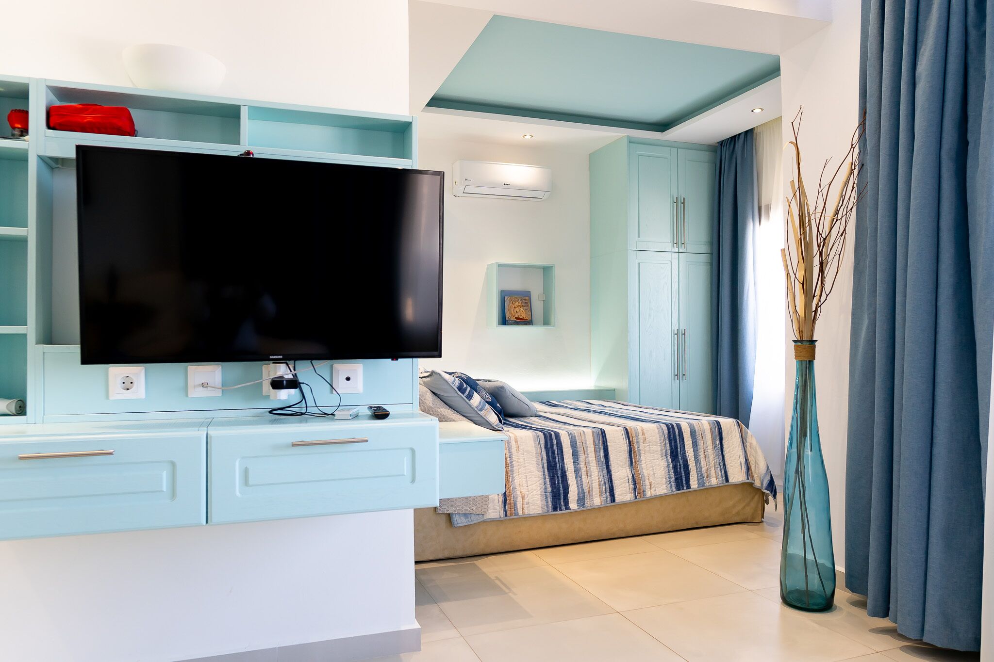 A modern bedroom with a bed, a TV, and a desk area.