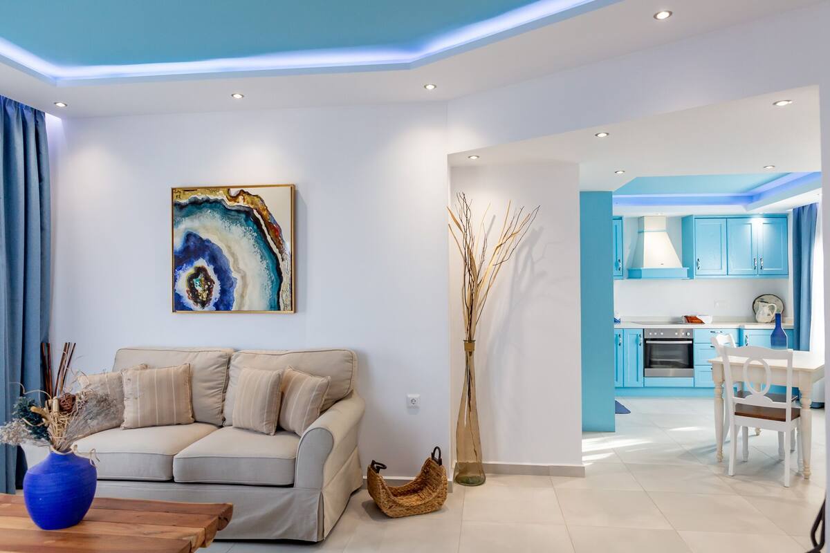 Un salon moderne avec un canapé beige, un vase bleu et un tableau accroché au mur.